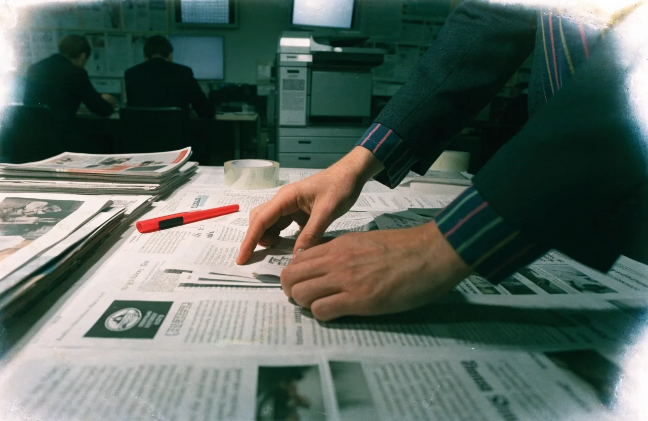 Handen die papierstroken knippen op de werktafel van de redactie